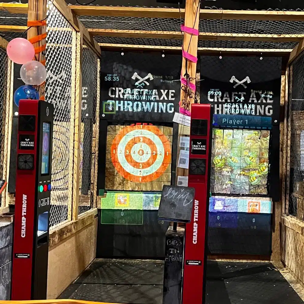 Digital scoring lanes at Craft Axe Throwing Columbia with wooden bullseye targets and screens above each lane